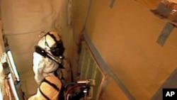 Technicians spray foam insulation on a section of repaired stringers on space shuttle Discovery's external fuel tank