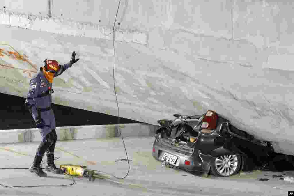 Polisi mengamati sebuah mobil yang ringsek di bawah jembatan yang ambruk di Belo Horizonte, Brazil, 3 Juli 2014. 