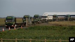 Some of the 150 trucks leave Manston Airfield during a 'no-deal' Brexit test, to assess where 6,000 trucks could be parked at the former airfield near Ramsgate in south east England, Monday, Jan. 7, 2019. (AP Photo/Matt Dunham)