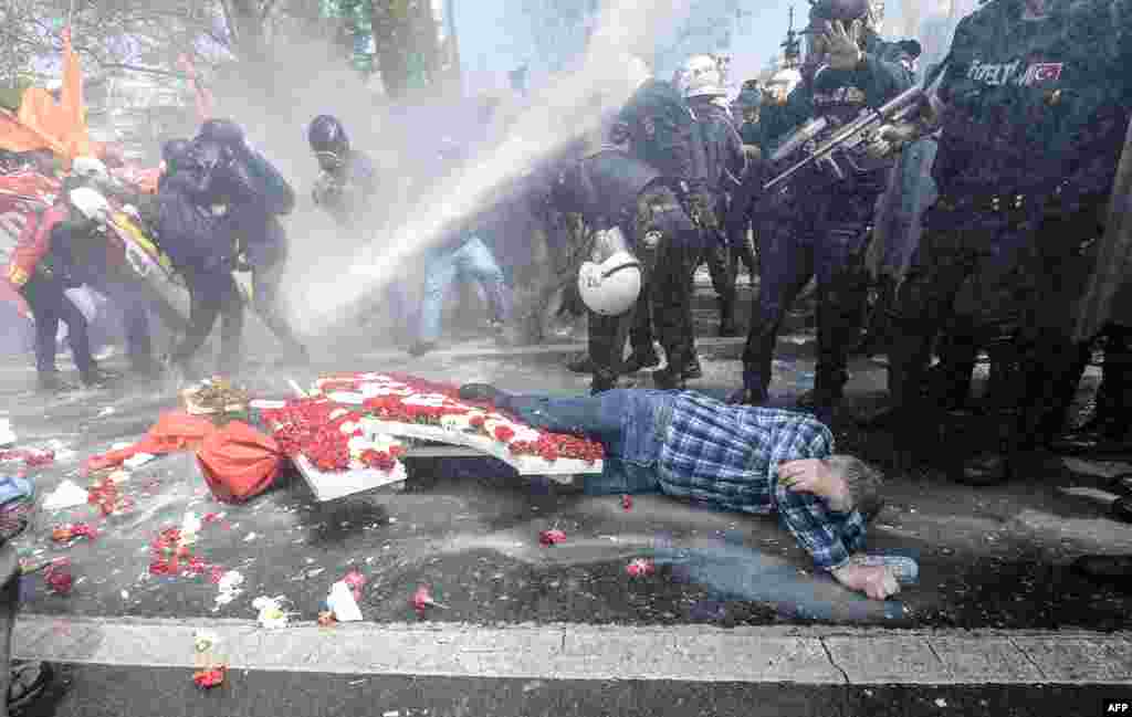 A man lies on the ground as Turkish police use a water cannon to disperse protestors during a May Day rally near Taksim Square in Istanbul, May 1, 2015.
