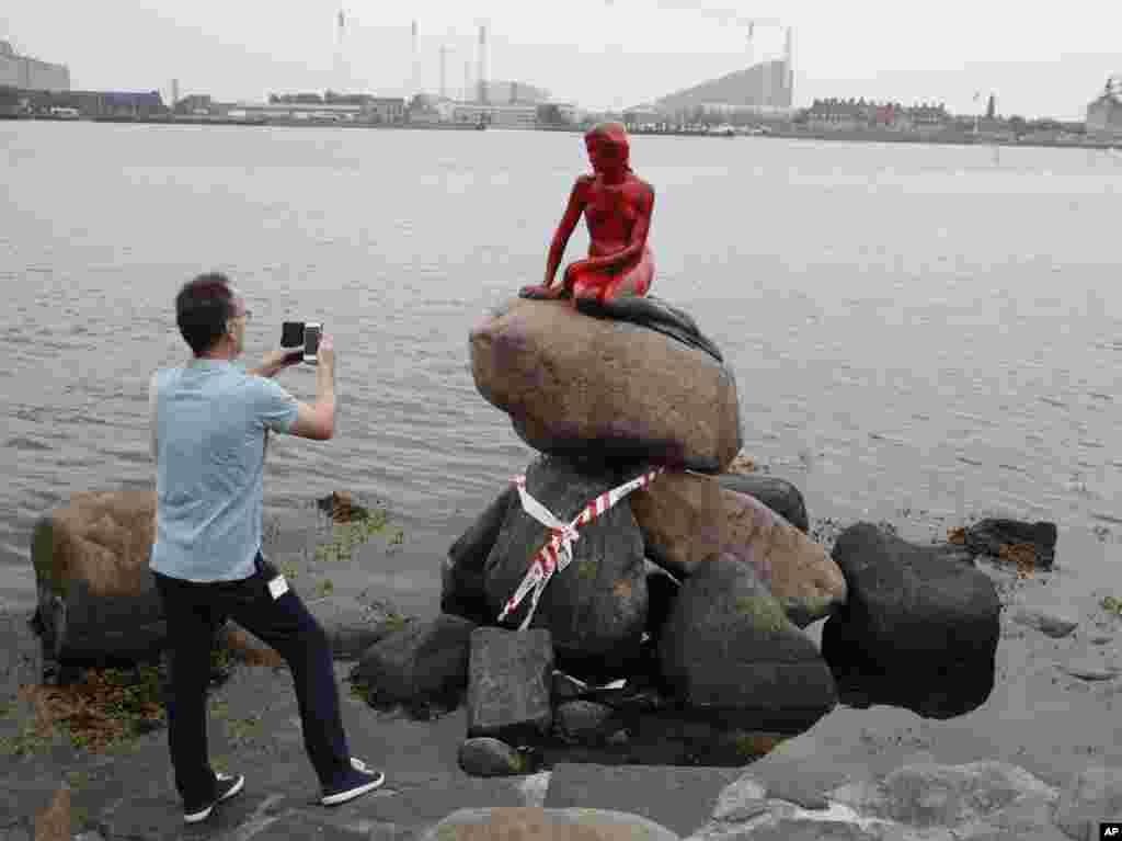 Seorang turis memotret patung 'Little Mermaid' yang menjadi korban vandalisme tangan-tangan jahil di Kopenhagen, Denmark.