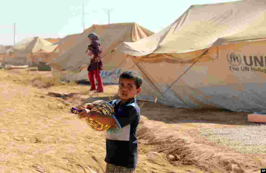 A Syrian refugee boy carries toys, clothes and pocket money received by Muslim children on the first day of Eid al-Fitr holiday, at Zaatari Refugee Camp in Mafraq, Jordan, Aug. 19, 2012.