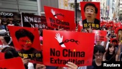 FILE - Demonstrators hold signs protesting an extradition bill during a rally in Hong Kong, June 9, 2019.