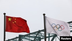 A Chinese national flag flutters next to an Olympic flag at the Beijing Organising Committee