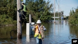 Dua pekerja berusaha memperbaiki jaringan listrik yang rusak akibat badai Matthew melanda Lumberton, North Carolina, Selasa (11/10).