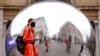A person wearing a face mask is reflected in an art work entitled "A=V" by Ben Cullen Williams, amid the coronavirus outbreak, in Covent Garden, London, Britain.