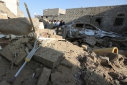 FILE - People stand at the site of a Houthi ballistic missile attack over the populated district of Rawda in Marib, Yemen, Feb. 6, 2020.