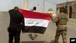 This image made from Associated Press video shows Iraqi soldiers carrying an Iraqi flag to put on buildings, after a senior Iraqi commander declared that the city of Fallujah was "fully liberated" from Islamic State group militants, in Fallujah, Iraq, Sunday