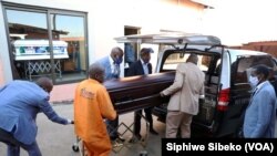 Des employés des pompes funèbres placent un cadavre dans un corbillard à Soweto, en Afrique du Sud, le 4 août 2020.