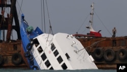 Para petugas berusaha mengangkat kapal ferry yang tenggelam di Pulau Lamma, Hong Kong (2/10).
