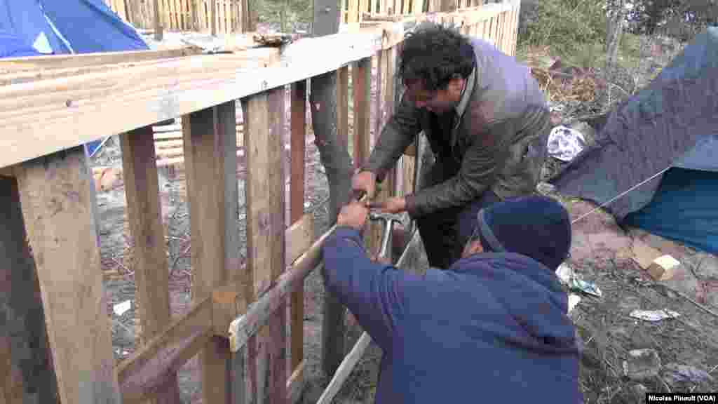 Deux migrants construisent un abri dans dans la "jungle". Ce camp est situé aux abords de Calais dans le nord de la France, 13 octobre 2015 (Nicolas Pinault/VOA).