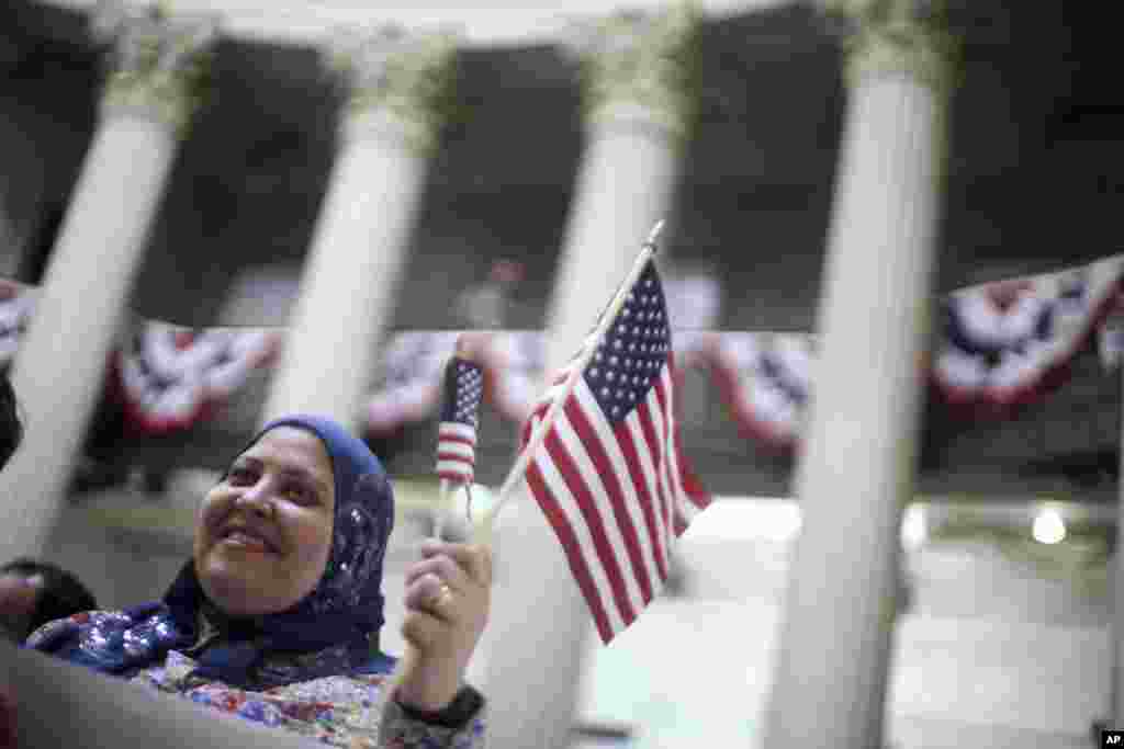 Fatma Atia, who is originally from Egypt and lives in New York, waves an American flag during a naturalization ceremony at Federal Hall, New York, March 22, 2013.