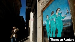Une femme portant un masque de protection passe devant un tableau représentant les vaccins Moderna, Pfizer et AstraZeneca, rue Bisbe, à Barcelone (Espagne), le 27 janvier 2021.