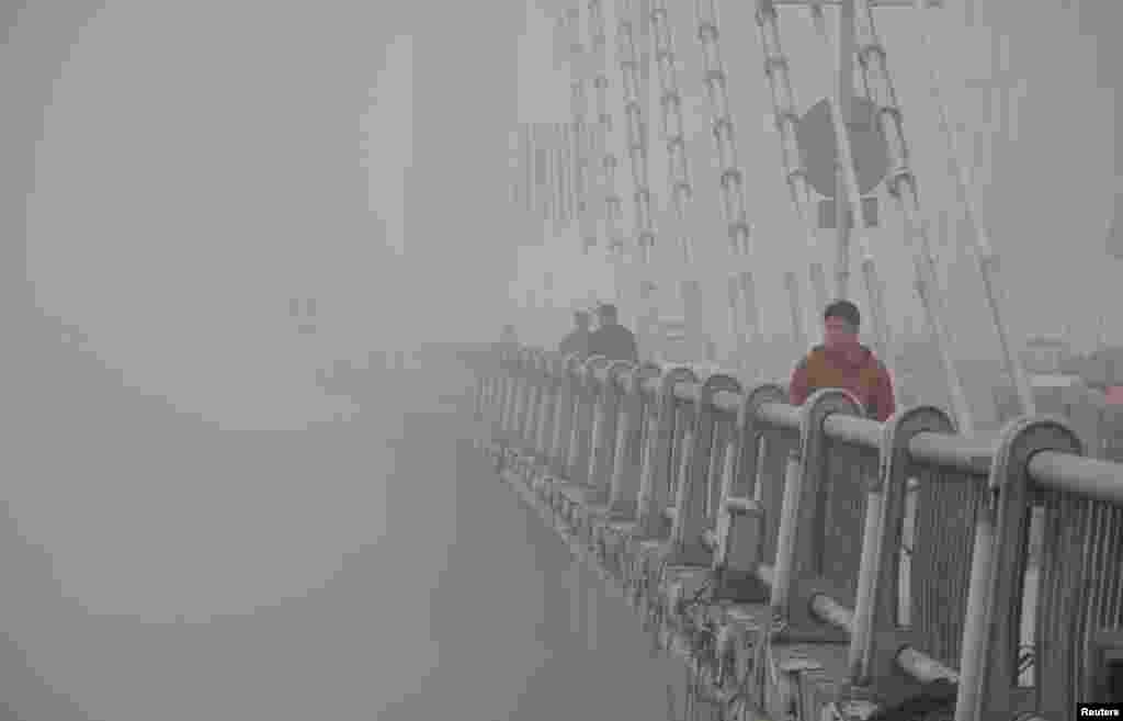 People walk on a bridge during a smoggy day in Jilin, Jilin province, Oct. 21, 2013.