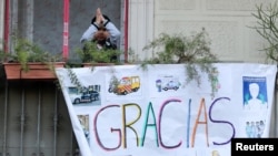 Un niño saluda desde un balcón en Barcelona, España, detrás de un cartel de apoyo a los trabajadores de la salud que luchan contra el coronavirus, el 11 de abril de 2020.