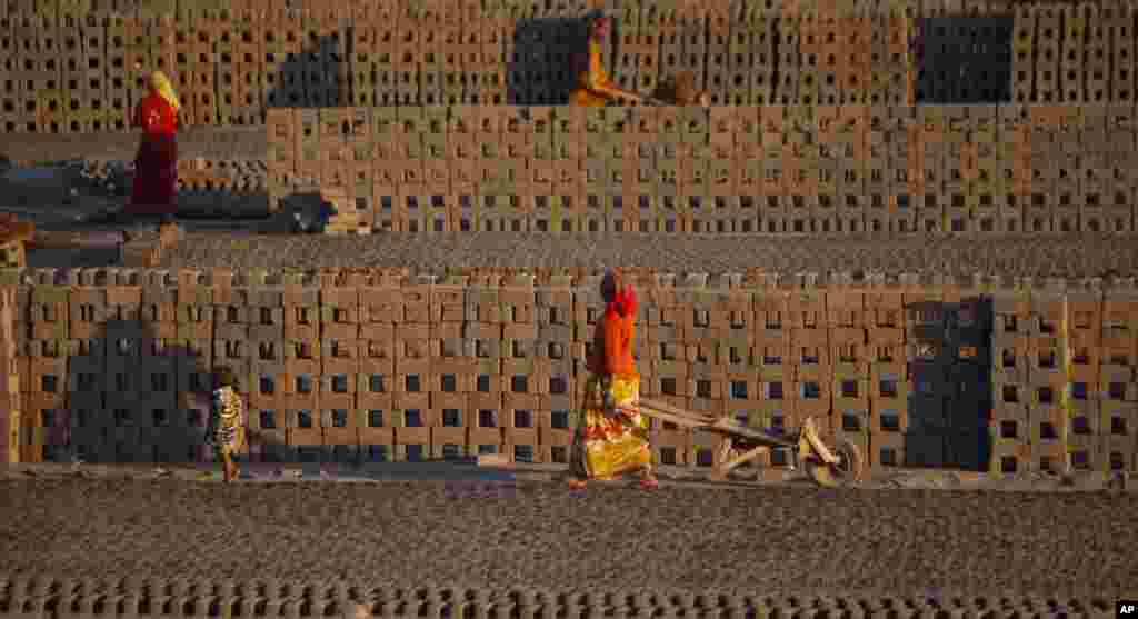 Laborers transport bricks on hand carts at a brick kiln factory on the outskirts of Jammu, India.