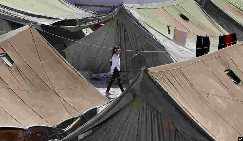 A Syrian refugee girl walks at a temporary refugee camp in the eastern Lebanese town of Marj near the border with Syria, August 28, 2013.