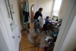 A mother watches as her son take a live class online at their home in San Francisco in this March 19, 2020, photo.