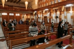 Iraqi Christians wear protective face masks, amid the outbreak of the coronavirus disease (COVID-19), as they attend a mass at a Church in Baghdad, Iraq, Feb. 22, 2021.