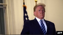 El presidente Donald Trump aparece en un balcón de la Casa Blanca después de regresar del hospital Walter Reed, el 5 de octubre de 2020.