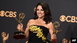 FILE - Julia Louis-Dreyfus poses in the press room with her awards for outstanding lead actress in a comedy series and outstanding comedy series for "Veep" at the 69th Primetime Emmy Awards at the Microsoft Theater in Los Angeles, Sept. 17, 2017.