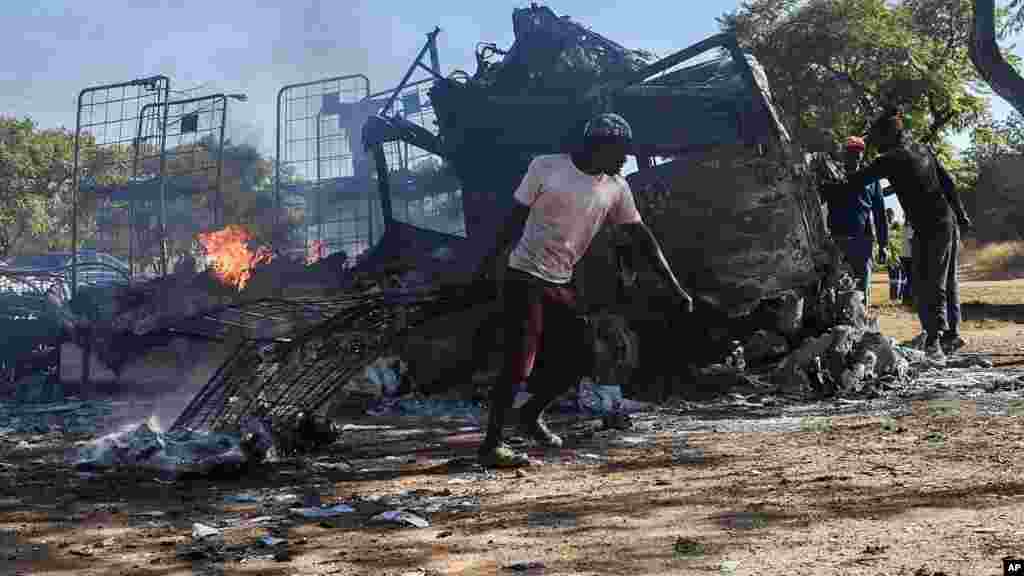 Un habitant passe devant un camion incendié près de la route où les manifestants sont passés à Atteridgeville, à l'ouest de Pretoria, Afrique du Sud, le 21 juin 2016.