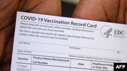 A healthcare worker displays a Covid-19 Vaccination Record Card at QueensCare Health Center in Los Angeles, California, Aug. 11, 2021.