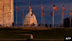 WASHINGTON, DC - DECEMBER 26: The US Capitol Building is seen past the Washington Monument as the sun sets on December 26, 2020 in Washington, DC. Lawmakers in Congress are continuing to work on the coronavirus relief package following President…