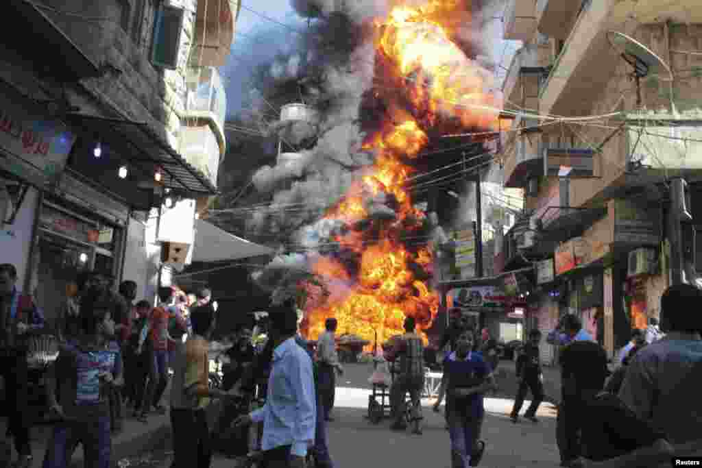 Residents run from a fire at a gasoline and oil shop in Aleppo's Bustan Al-Qasr neighborhood, Oct. 20, 2013.