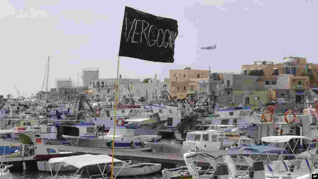 A black flag with writing reading in Italian "Vergogna" (shame) waves in the harbor of the island of Lampedusa, Italy, Oct. 4, 2013.
