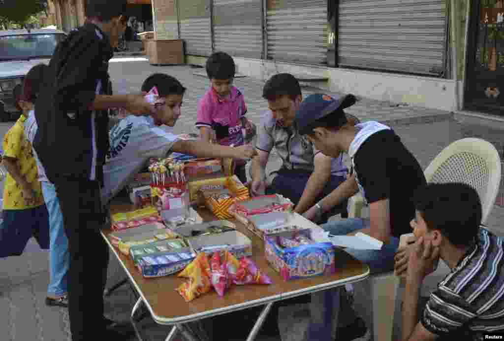Children buy candies as they celebrate Eid al-Fitr in the Duma neighborhood of Damascus, Syria, August 8, 2013. 