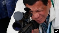 FILE - Philippine President Rodrigo Duterte checks the scope of a Chinese-made CS/LR4A sniper rifle, June 28, 2017.