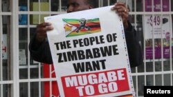 Um homem com um cartaz que diz "O povo quer que Mugabe saia" Nov. 18, 2017. 