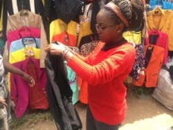 Emily Mugure checks out a secondhand jacket in Nairobi's Toi market. (M. Yusuf/VOA)