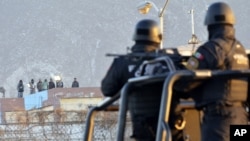 FILE - Inmates stand on the rooftop of the Topo Chico prison as police guard the perimeters after a riot broke out around midnight in Monterrey, Mexico, Feb. 11, 2016. 
