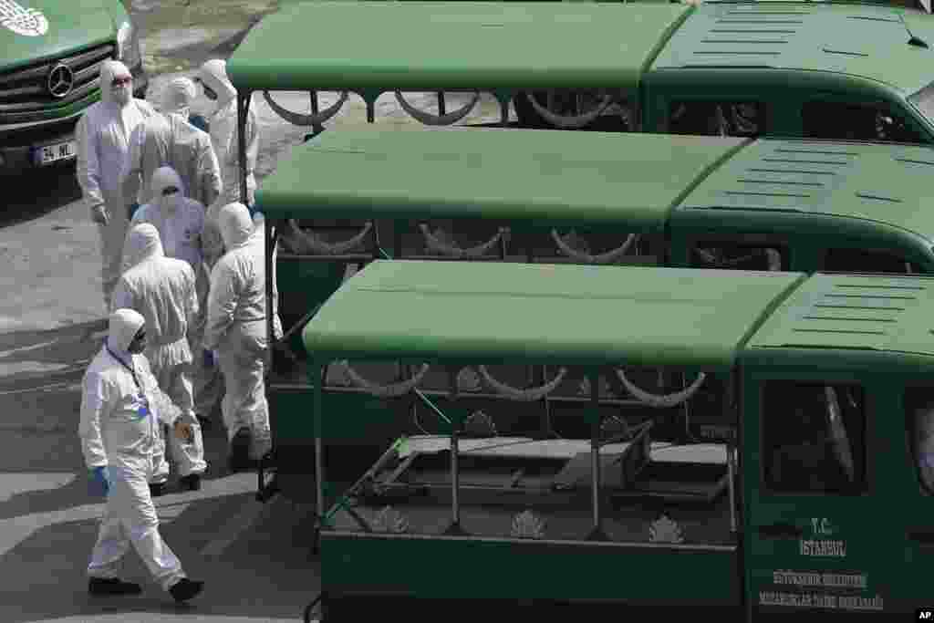 Los funcionarios, con máscaras y trajes protectores como medida preventiva contra la propagación del coronavirus, esperan para cargar ataúdes de víctimas de Covid-19, afuera de una morque en Estambul.