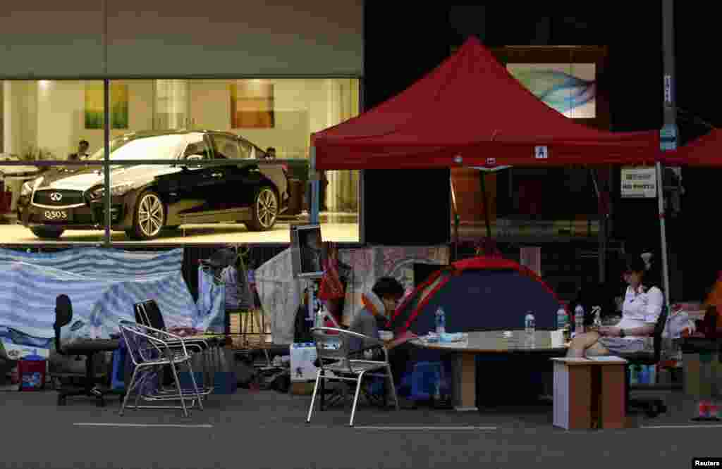 Pemrotes pro-demokrasi duduk di jalanan, depan sebuah ruang pamer mobil di pusat distrik keuangan Hong Kong, 6 November 2014.