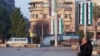 FILE - On Jan. 8, 2025 — about a month after the ouster of Syrian leader Bashar al-Assad — a man sits in Aleppo, Syria, near flags reflecting new leadership. Diplomats from around the world are pushing to stabilize Syria in the wake of Assad's fall. 