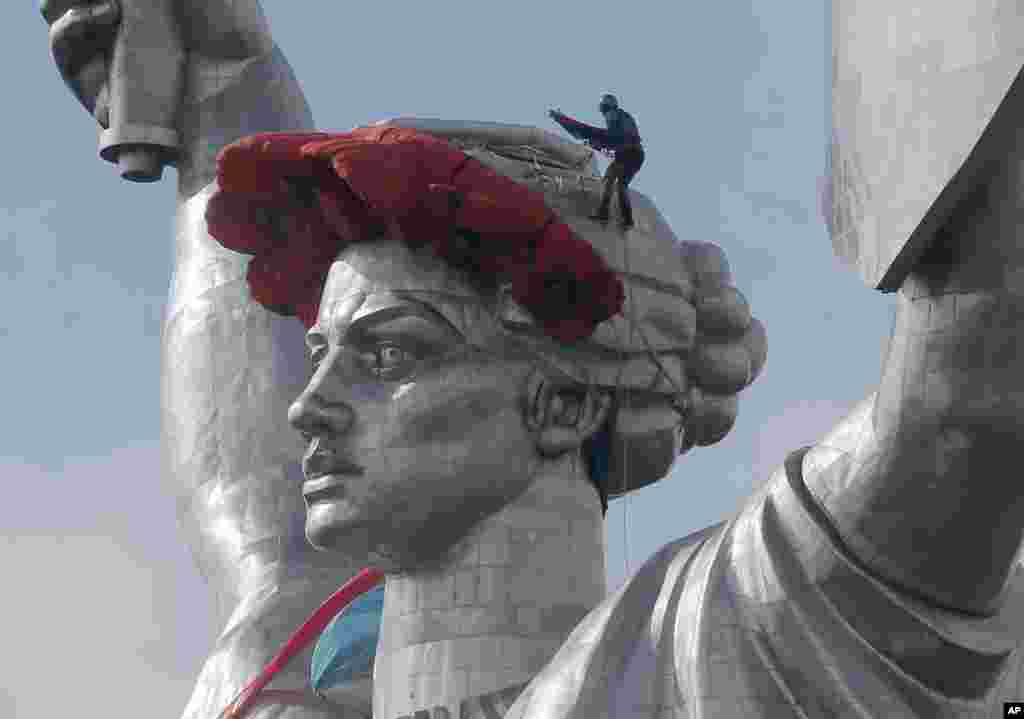 A worker installing a wreath of poppies as a red peak and ribbon on top of the 102-meter Motherland Monument in Kyiv, Ukraine, May 8, 2015, to mark the anniversary of the defeat of the Nazis in WWII.