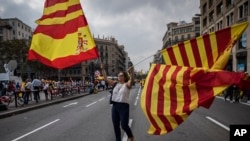 A woman waves flags of Catalonia and Spain as people celebrate a holiday known as "Dia de la Hispanidad" or Spain's National Day in Barcelona, Spain, Oct. 12, 2017. 