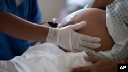 FILE - A pregnant woman is examined as she waits to give birth at a hospital in Rio de Janeiro, Brazil, July 25, 2012