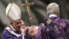 Pope Benedict XVI sprinkles ashes on Cardinal Tarcisio Bertone (C) during the Ash Wednesday mass at the Vatican February 13, 2013. 