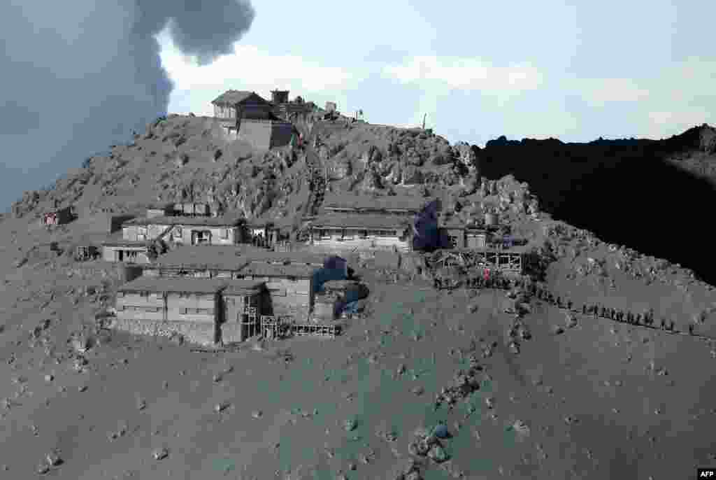 Foto yang diambil dari udara ini memperlihatkan aktivitas regu penyelamat dan para anggota Pasukan Bela Diri Jepang (JSDF) dalam operasi pencarian korban erupsi gunung Ontake, di antara timbunan debu yang menyelimuti desa-desa dan sebuah kuil Shinto di wilayah Nagano, Jepang (28/9).