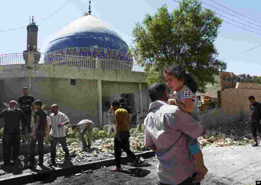 People clean up after a car bomb attack hit a Shi'ite mosque in Bayaa, Baghdad, July 29, 2013.