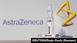 A test tube labeled with the vaccine is seen in front of AstraZeneca logo