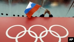 Un supporter russe tenant le drapeau de son pays juste au dessus de l'emblème du CIO, Russie le 18 février 2014.