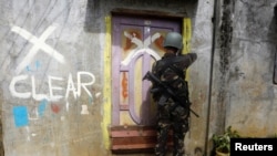 A member of the Philippine National Police (PNP) closes a door after marking a house as clear while government troops continue their assault against insurgents from the Maute group in Marawi city, June 29, 2017.