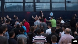 Para pengunjuk rasa menggoyang-goyangkan bus polisi di kota Mytilene di bagian timur pulau yang terletak di Laut Aegea, yaitu pulau Lesbos, 3 Mei 2018 (foto: AP Photo/Petros Giannakouris)
