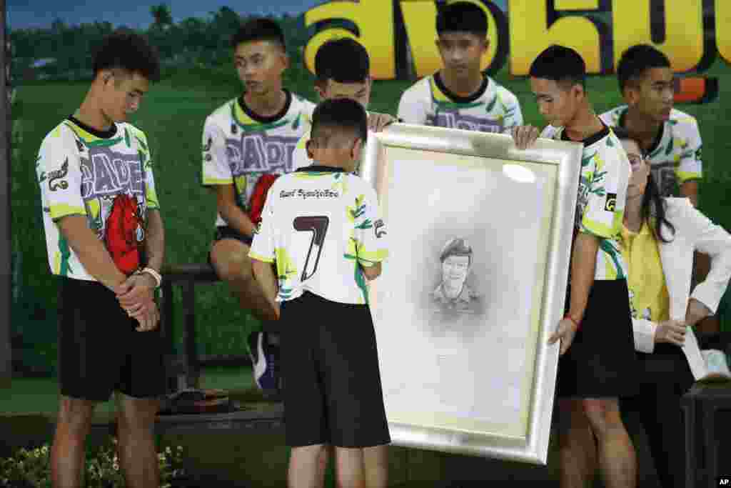 គ្រូបង្វឹក Ekkapol Janthawong (ឆ្វេង) និងកុមារ១២នាក់ក្នុងក្រុមបាល់ទាត់ដែលបានជាប់ក្នុងល្អាងភ្នំផ្តល់ការគោរពដល់លោក Saman Gunan អ្នកមុជទឹក Thai SEAL ចូលនិវត្តន៍ម្នាក់ដែលបានស្លាប់អំឡុងការសង្រ្គោះដំបូងរបស់ពួកគេ នៅក្នុងសន្និសីទកាសែតក្នុងទីក្រុងឈៀងរ៉ៃប្រទេសថៃ។
