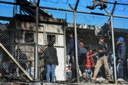Migrants stand outside container houses in Moria refugee camp on the northeastern Aegean island of Lesbos, Greece, March 16, 2020.